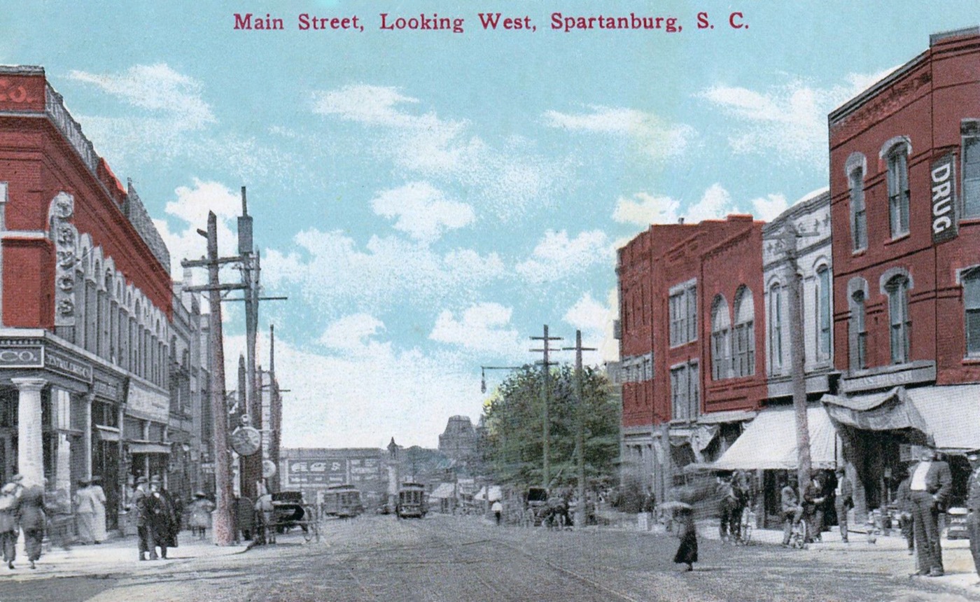 Main Street looking west, around 1910, with brick storefronts and awnings
